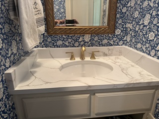 Finished bathroom vanity with marble countertop and floral wallpaper
